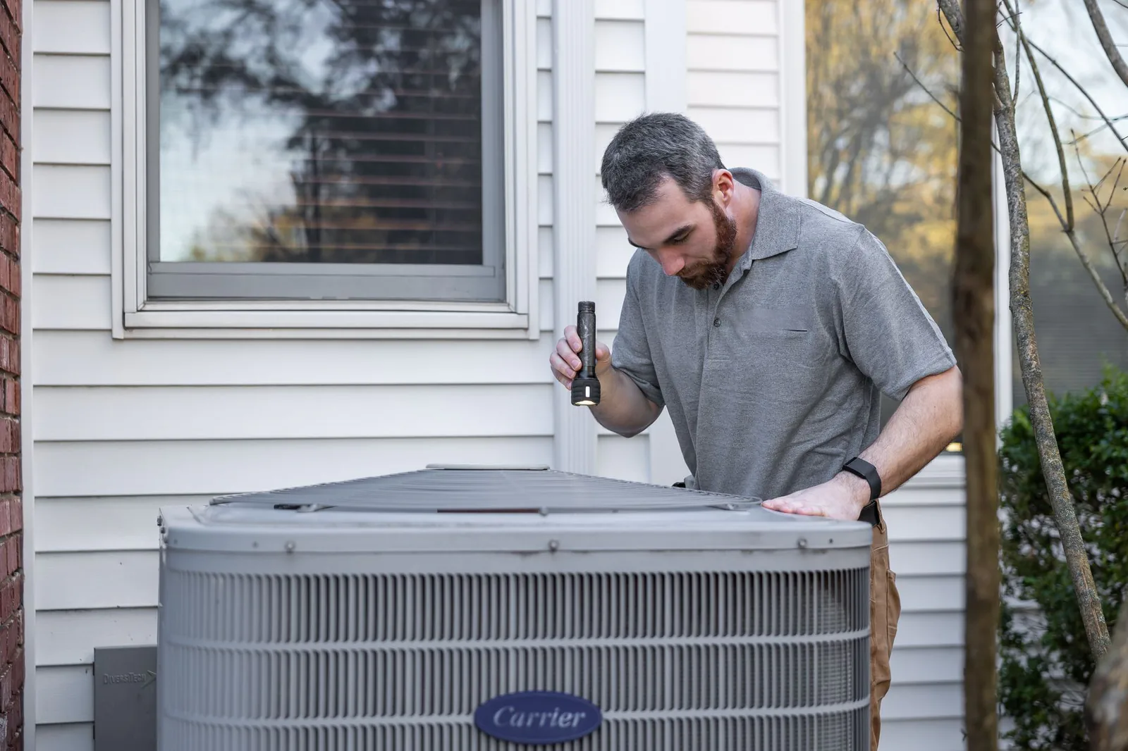 HVAC technician inspecting an outdoor condenser unit